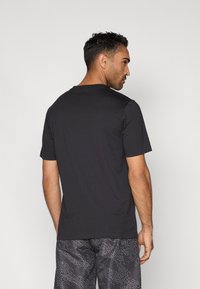 Svart T-skjorte med korte ermer og rund hals, laget av myk bomull. Har et enkelt design, uten synlige mønstre eller detaljer.