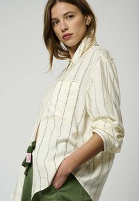 Chemise crème à rayures florales verticales vertes, col classique, fermeture à boutons et poche poitrine ; assortie avec un pantalon vert.