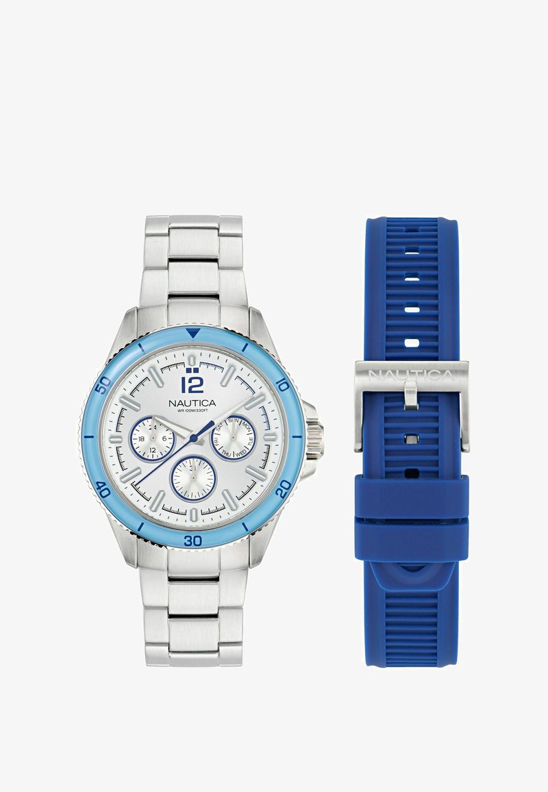 Orologio in acciaio inossidabile con lunetta blu e quadrante bianco, dotato di tre sottoquadranti. Include un bracciale in silicone blu. Marchio Nautica visibile.