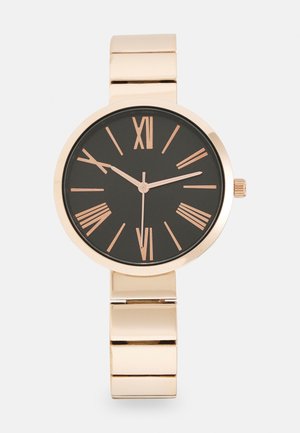 Montre-bracelet en or avec cadran noir, chiffres romains en or rose, et bracelet à maillons métalliques affichant l'heure 2:49:30.