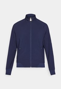 Navy zip-up jacket with high collar, textured side panels, and two side pockets. Soft, stretchy fabric with perforated detailing.