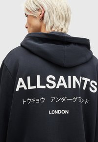 Felpa nera con cappuccio con un grande logo bianco "ALLSAINTS" sulla schiena, con testo aggiuntivo in giapponese e "LONDON" in basso. Tessuto morbido, vestibilità casual.