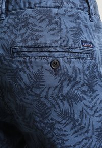 Blå mönstrade shorts med ett ormbunksmönster, gjorda av mjukt tyg, med en bakficka och en enda svart knapppunkt.