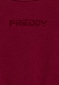 Felpa girocollo color bordeaux realizzata in un tessuto morbido e testurizzato. Logo "FRDDY" in rilievo di una tonalità più scura, centrato sulla parte anteriore.