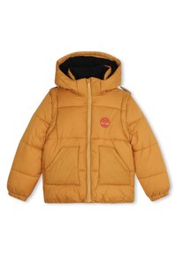 Giacca a vento color miele con cappuccio, chiusura frontale con zip e due grandi tasche. Presenta un piccolo logo rosso sul petto e un rivestimento interno nero.