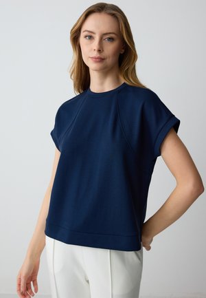  Haut bleu marine à manches courtes avec un col rond, au fit décontracté et à la texture douce, complété par des poignets de manches roulés.