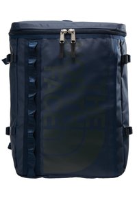 Sac à dos rectangulaire bleu marine avec deux zippers supérieurs, des sangles de compression latérales et le logo "The North Face" sur le devant.