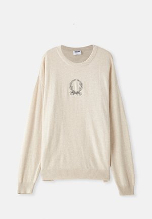 Bež pleteni pulover z rebrastim robom in manšetami, ki v središču vsebuje vezeno okroglo lovorovo zasnovo. Oblika s krojnim vratom.