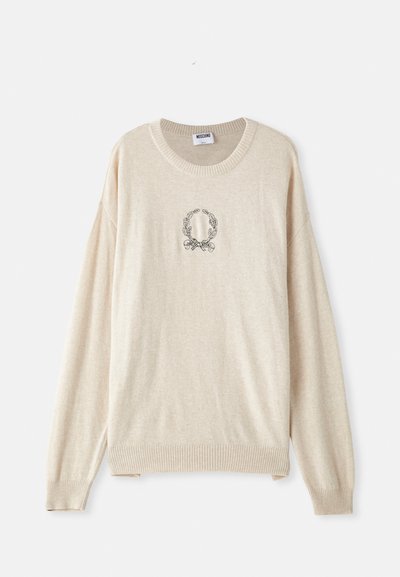 Beige Strickpullover mit geripptem Saum und Bündchen, der in der Mitte ein besticktes, kreisförmiges Lorbeerdesign aufweist. Rundhalsausschnitt.