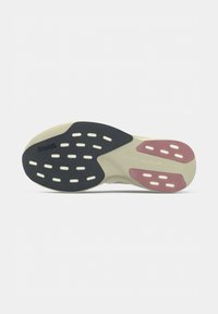 Semelle de chaussure de course avec plots d’adhérence noirs et roses, base beige et marquage Continental sur la partie noire.