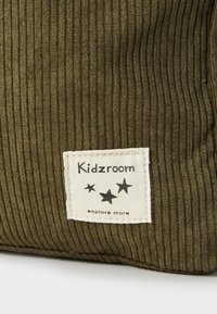 Žalias aksominis maišelis su etikete "Kidzroom" ir žvaigždžių dizainu. Tekstūra yra minkšta, su įprastu balto ženklelio kontrastu.