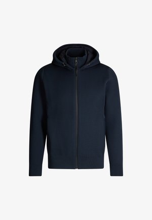 Felpa con zip di colore blu navy in tessuto texturizzato, con cappuccio e tasche laterali. Presenta polsini e orlo a costine con un rivestimento interno liscio.