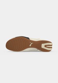 Semelle de chaussure Puma beige et marron avec grip texturé et logo Puma au centre, affichée sur fond blanc.