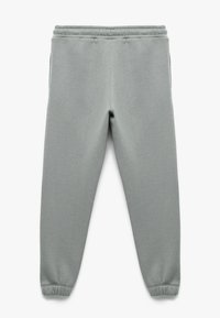 Light grey sweatpants made of soft fabric. Features an elastic waistband and fitted cuffs. Two side pockets visible at the hips.