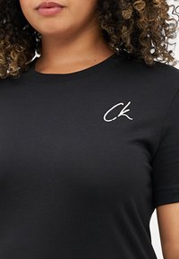Μαύρο βαμβακερό μπλουζάκι με στρογγυλή λαιμόκοψη, διαθέτει κεντημένο λευκό λογότυπο "CK" στην αριστερή πλευρά του στήθους. Λείο υλικό, κοντά μανίκια.
