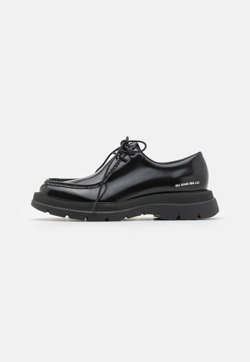 Black leather dress shoe with a rounded toe, thick rubber sole, lace-up design, and distinctive stitching along the edge.