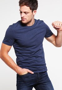 T-shirt a maniche corte blu navy in morbido tessuto, con collo a giro e design aderente, abbinato a jeans scuri.