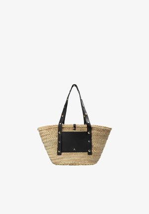 Bolsa tote de paja tejida con anchas correas de cuero negro y bolsillo frontal, adornada con tachuelas metálicas y un pequeño emblema de calavera.