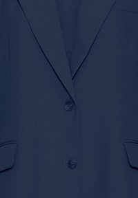 Tengerészkék blézer bevágott gallérral, egysoros, két gombos, két első zsebbel. Sima textúra és szabott szabás.