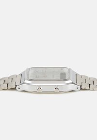 Montre analogique en acier inoxydable argenté avec un boîtier carré, un bracelet métallique et un verre clair. Comprend deux boutons-poussoirs sur le côté.