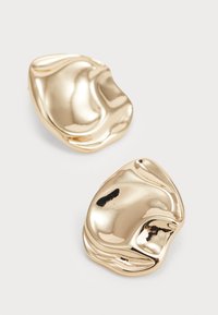 Χρυσά μεταλλικά σκουλαρίκια με οργανικό, αφηρημένο σχήμα, διαθέτοντας λείες, γυαλιστερές επιφάνειες και απαλά καμπύλες. Χωρίς ορατές συνδέσεις ή μοτίβα.