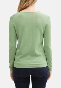 Pull vert à manches longues avec un col rond, texture côtelée et silhouette ajustée. Pas de quincaillerie ou de motifs notables.