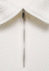 Weißer Zip-up-Pullover mit strukturiertem Strickdesign. Verfügt über einen silbernen Reißverschluss und einen hohen Kragen. Weicher Stoff mit diagonalen Reliefmustern.