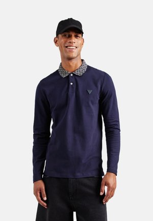 Polo de manga larga en color marino con cuello estampado y logotipo en el pecho. Hecho de algodón con una textura suave. Corte casual para un uso versátil.