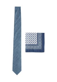 Denim kravata i uzorčana marama, oboje u nijansama plave. Kravata ima teksturiranu završnicu; marama sadrži geometrijske uzorke i rubove.