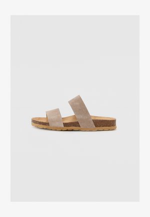 Sandali slide in suede beige con due ampi cinturini, soletta in sughero e suola in gomma. Design piatto con uno stile minimalista e senza hardware visibile.
