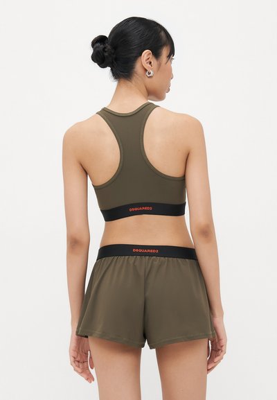 Olive green sports bra and shorts set. Bra features a racerback design with a black band; shorts have a wide elastic waistband and loose fit.