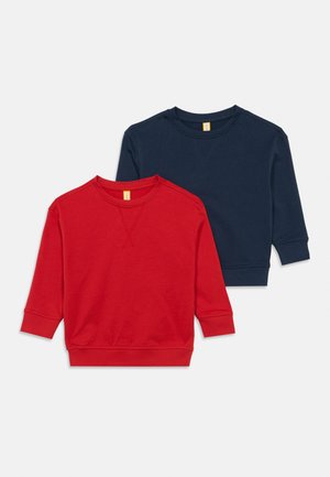 To ensfarvede crewneck-trøjer, den ene rød delvist lagdelt over en mørkeblå, vist på en lysegrå baggrund.