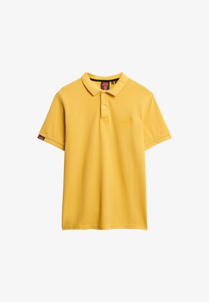 Camisa polo amarilla de manga corta con cuello, presenta una tapeta de tres botones y bordado del logo en el pecho. Tejido suave y texturizado.