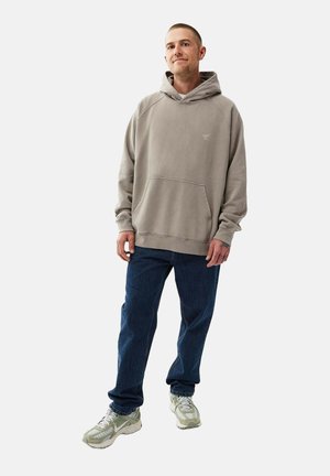 Grå hættetrøje med kængurulomme og ribbede manchetter, parret med mørkeblå jeans og lyse sneakers. Enkel, afslappet pasform.