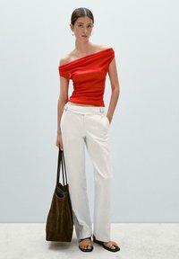 Red off-the-shoulder top, white wide-leg pants with silver hardware accents, brown suede tote bag, and black flat sandals on a neutral background.