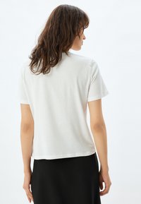 Hvid bomulds T-shirt med korte ærmer og afslappet pasform. Glat tekstur og et enkelt design med rund hals. Velegnet til afslappet brug.