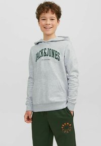 Sudadera gris con bolsillo tipo canguro, con el logo verde "JACK & JONES". Combinada con pantalones de chándal verde oscuro con estampado naranja.