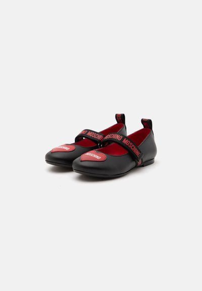 Chaussures Mary Jane noires et rouges avec le nom de la marque Moschino sur le patch avant et les brides, semelle plate et languettes au talon.