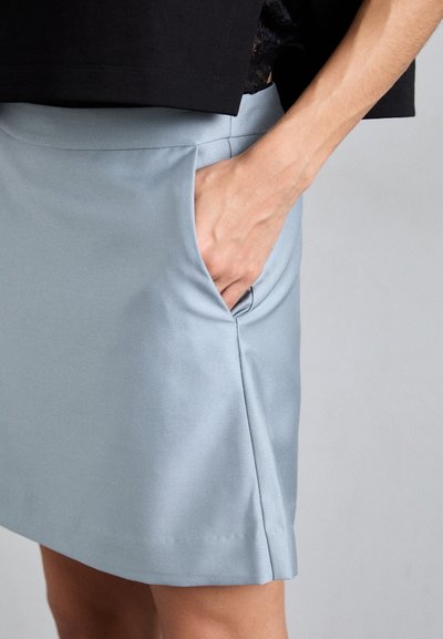 Ανοιχτό μπλε φούστα φτιαγμένη από απαλό ύφασμα, με πλαϊνές τσέπες και καθαρό στρίφωμα. Ο σχεδιασμός έχει κομψή εφαρμογή με διακριτές ραφές.