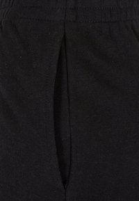 Gros plan d'un vêtement en tissu noir avec une ceinture élastique et une fente verticale ou une ouverture au centre devant.