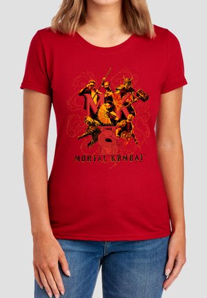 Woman wearing red Mortal Kombat graphic t-shirt with multiple characters and text centered on the front, paired with blue jeans.