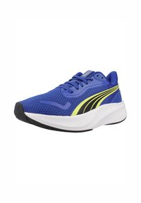 Zapatilla deportiva azul con parte superior de malla, que presenta detalles en amarillo y negro. La suela es blanca con un dibujo texturizado negro para mayor agarre.