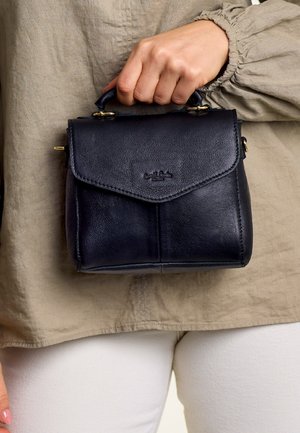 Small dark blue leather handbag with a folding flap, top handle, and gold hardware accents. Smooth texture and minimal branding visible.