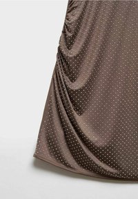 Tissu marron orné de petits points en relief, espacés régulièrement, couvrant la surface et créant un motif texturé.