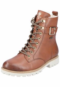 Brązowy skórzany botek za kostkę ze złotym okuciem, czarno-brązowymi sznurówkami we wzory oraz białą gumową podeszwą z grubożebrowym wzorem.