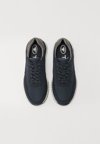 Chaussures de sport bleu foncé avec dessus en mesh, accents gris et semelle à motif. Dotées de lacets et d'un logo circulaire sur la languette.