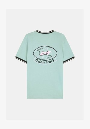 T-shirt vert clair à manches courtes avec col et poignets rayés noirs et blancs, ornés d'un nœud rose et du texte « Eden Park » au dos.