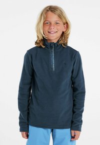 Marinblå fleecepolo med halv dragkedja, hög krage och logotypdetalj på framsidan. Långa ärmar och en mjuk struktur, perfekt för lager på lager.