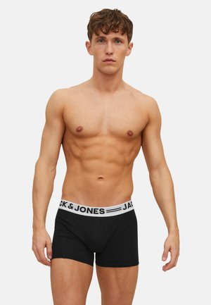 Schwarze Boxershorts mit einem weißen elastischen Bund, der den Schriftzug "JACK & JONES" trägt. Glatter Stoff mit einem eng anliegenden, figurbetonten Design.