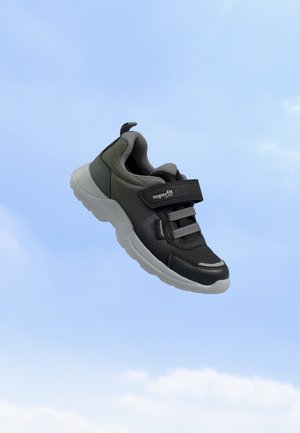 Børnesneakers i sort og grå med velcrolukning og elastiske snørebånd, der svæver mod en blå himmel baggrund.